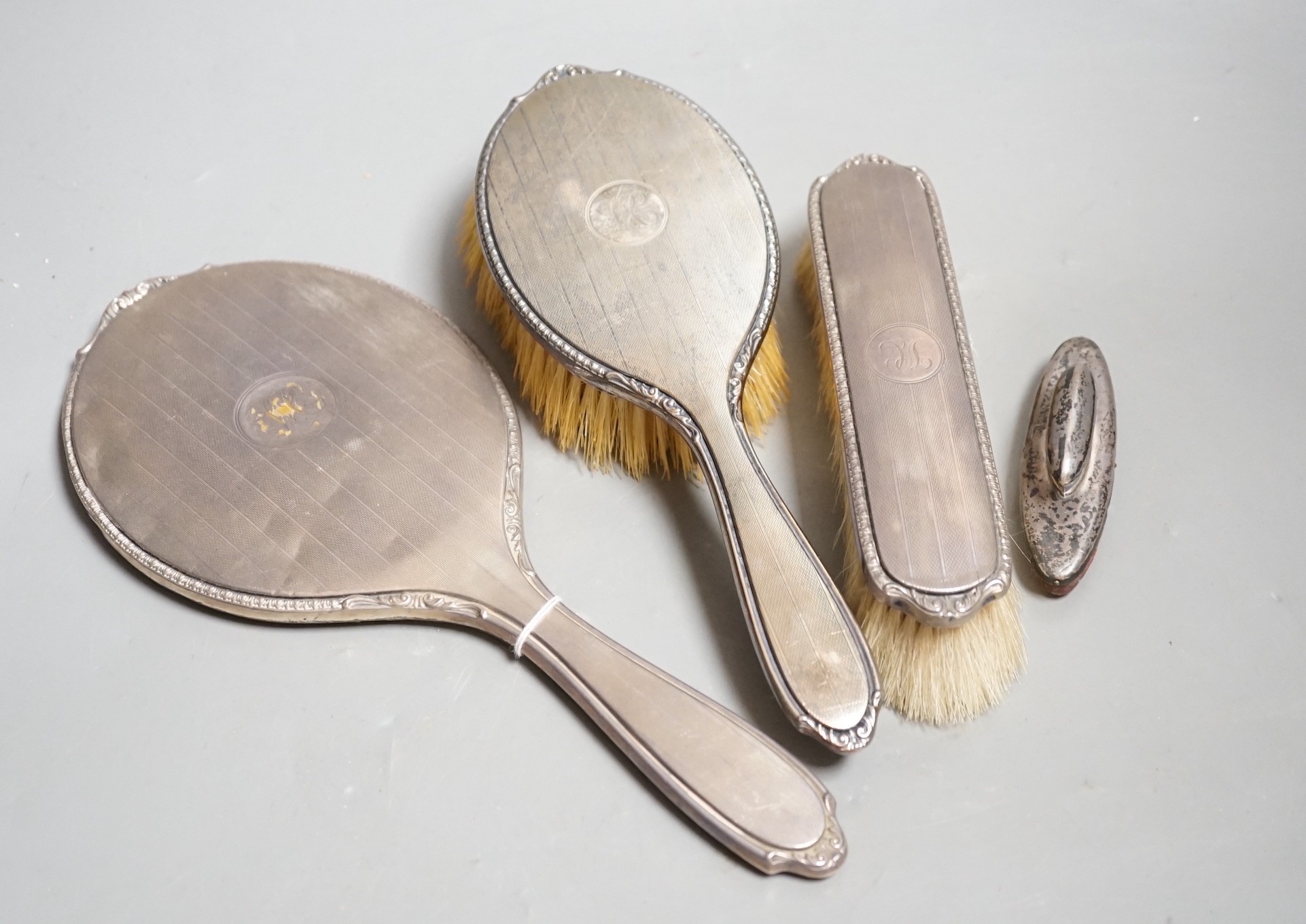 A George V silver mounted hand mirror and similar hair and clothes brush, Adie Bros. Birmingham, 1925 and a silver mounted nail buffer.